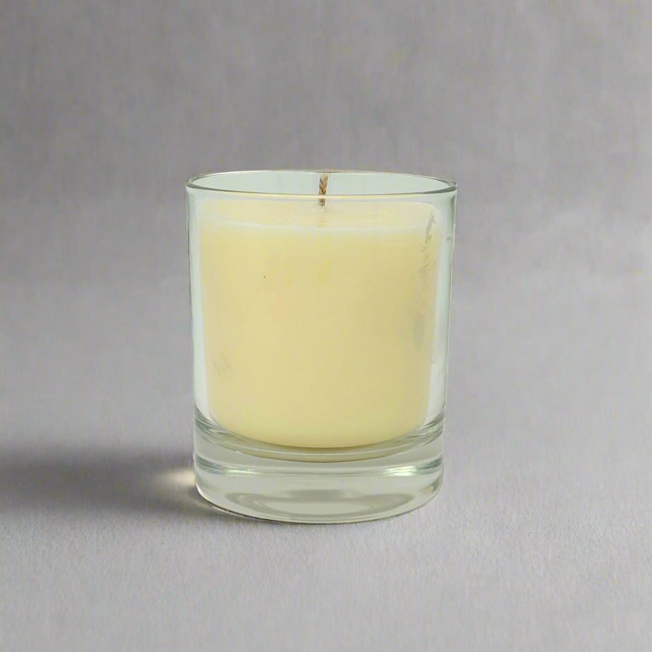 Clear glass candle holder with a white candle on a white background