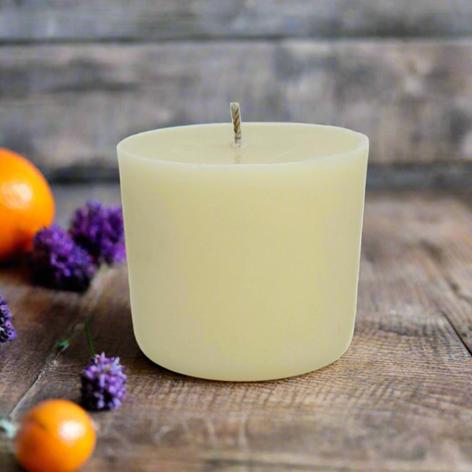 White candle refill on a wooden surface with oranges and lavender flowers