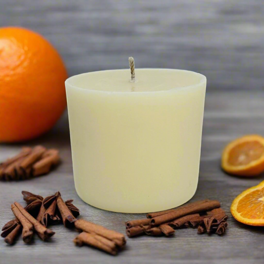White candle refill with cinnamon sticks and oranges on a wooden surface