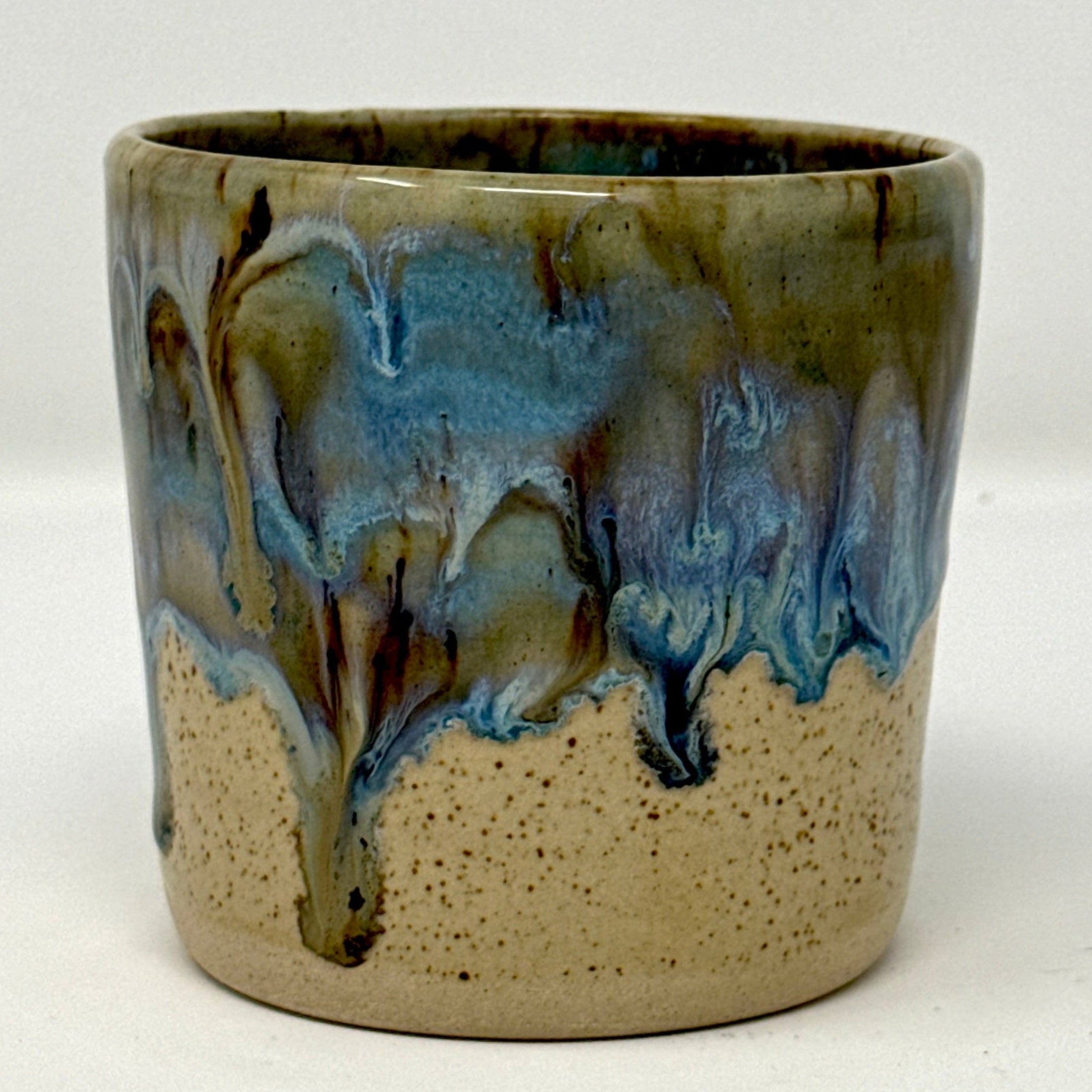 Ceramic cup with blue and brown glaze on a white background